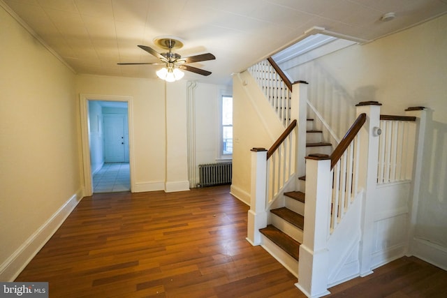 stairway with a ceiling fan, radiator, wood finished floors, and baseboards