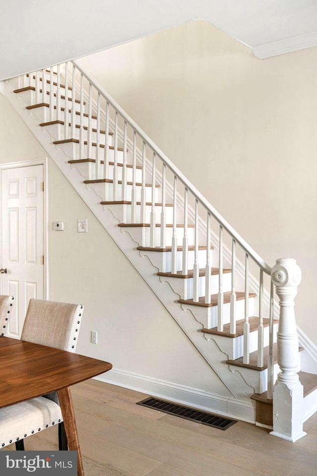 stairway featuring visible vents, baseboards, and wood finished floors