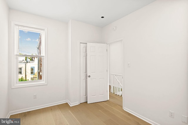 unfurnished bedroom featuring a closet, light wood-type flooring, and baseboards