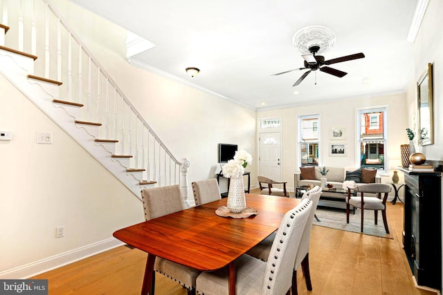 dining area featuring light wood finished floors, stairs, baseboards, and ornamental molding