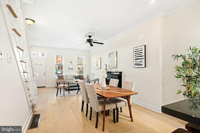 dining space featuring visible vents, baseboards, light wood-style floors, and crown molding