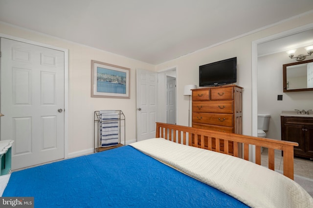 bedroom featuring ensuite bath, crown molding, baseboards, and a sink