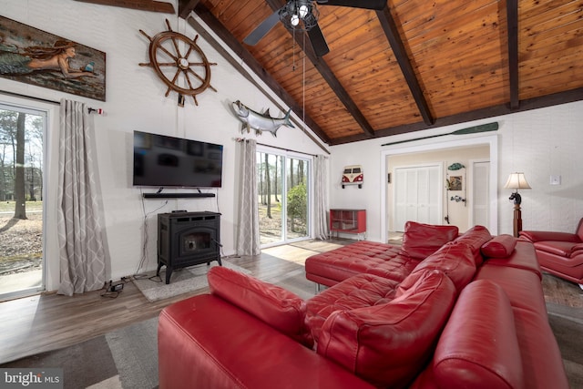 living area with beam ceiling, high vaulted ceiling, wood finished floors, wood ceiling, and a wood stove