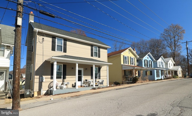 view of front of house featuring roof with shingles, covered porch, a residential view, and a chimney