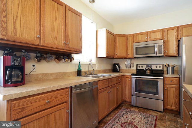 kitchen featuring light countertops, brown cabinetry, appliances with stainless steel finishes, and a sink