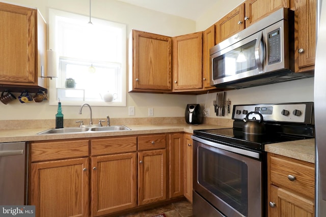 kitchen featuring a sink, stainless steel appliances, light countertops, pendant lighting, and brown cabinets