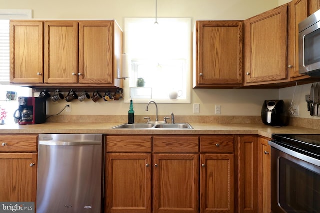 kitchen with brown cabinets, appliances with stainless steel finishes, light countertops, and a sink