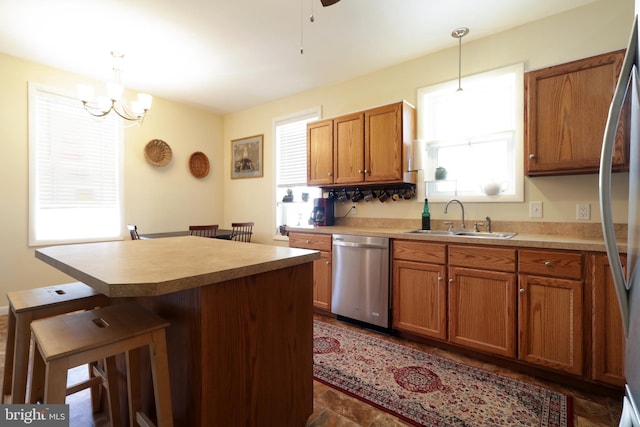 kitchen featuring a kitchen island, a sink, stainless steel appliances, a kitchen bar, and brown cabinets