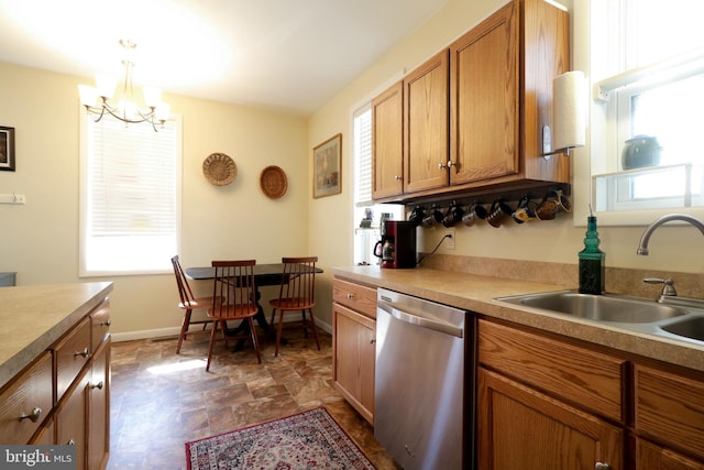 kitchen with brown cabinets, a sink, stainless steel dishwasher, an inviting chandelier, and baseboards