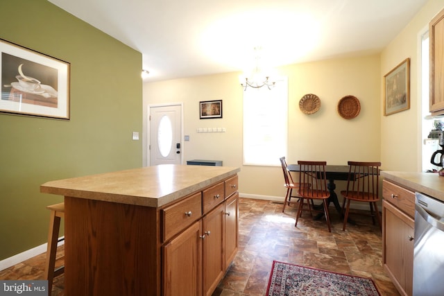 kitchen with a kitchen island, baseboards, a breakfast bar area, an inviting chandelier, and stainless steel dishwasher