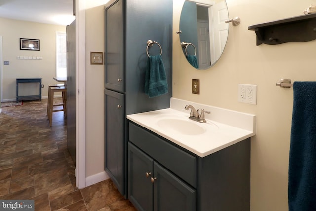 bathroom featuring stone finish flooring, baseboards, and vanity