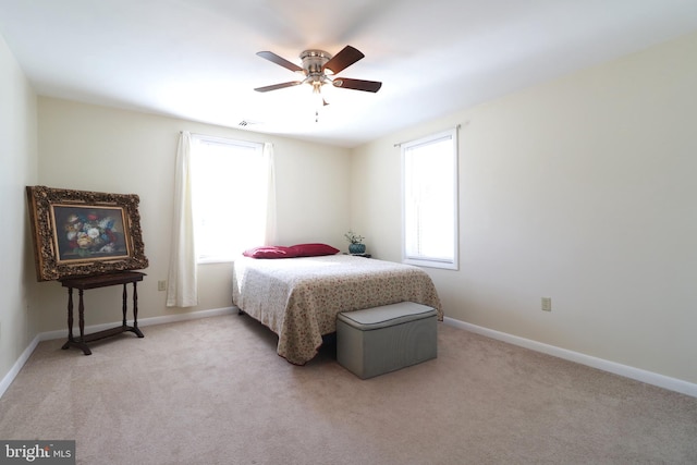 bedroom with a ceiling fan, baseboards, and light carpet