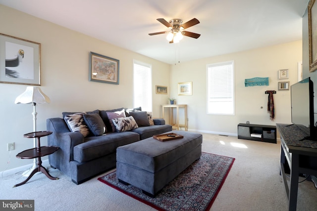 carpeted living room featuring baseboards and ceiling fan