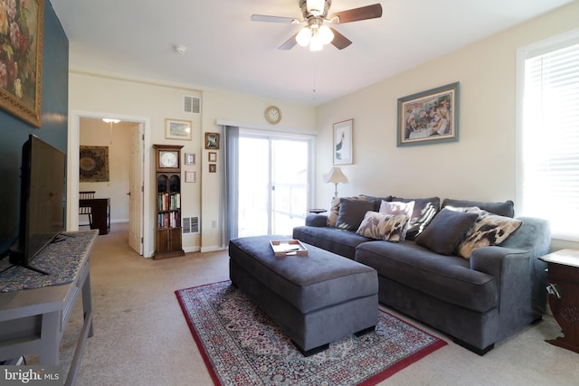 living room featuring visible vents, baseboards, light colored carpet, and a ceiling fan