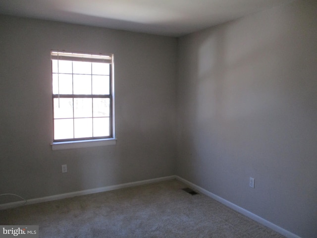 unfurnished room featuring visible vents, carpet floors, and baseboards