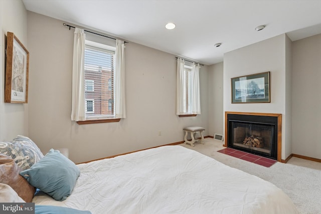 bedroom with a fireplace with flush hearth, visible vents, baseboards, and carpet