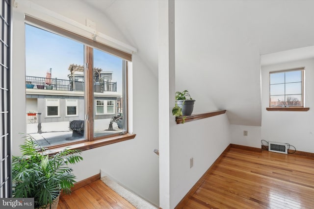 interior space featuring vaulted ceiling, baseboards, visible vents, and wood-type flooring