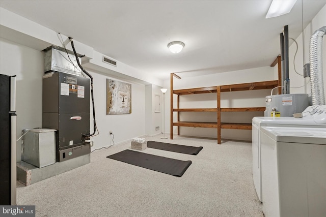 finished basement with visible vents, water heater, freestanding refrigerator, carpet, and washing machine and clothes dryer