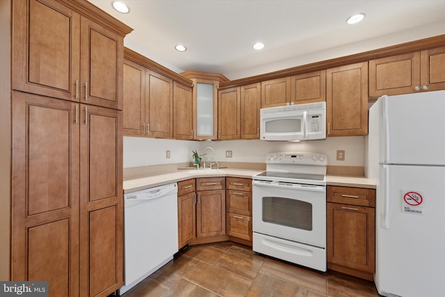 kitchen with a sink, white appliances, and brown cabinets