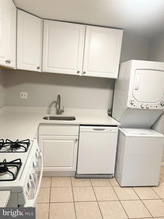 washroom featuring a sink, stacked washer and dryer, laundry area, and light tile patterned floors