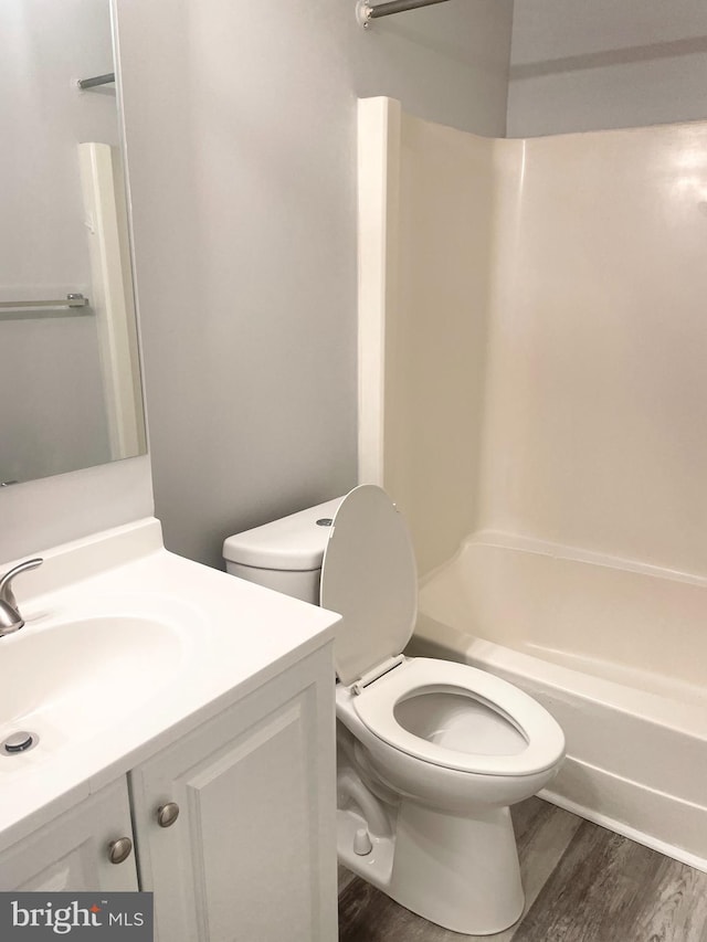 full bath featuring toilet, wood finished floors, vanity, and shower / tub combination