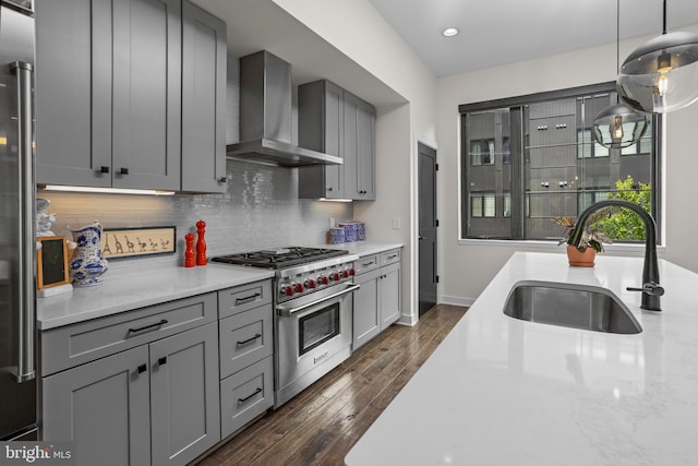 kitchen with a sink, stainless steel appliances, gray cabinetry, and wall chimney range hood