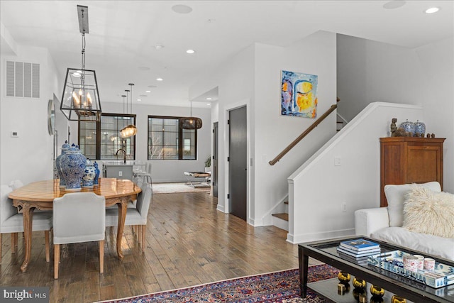 dining room featuring visible vents, hardwood / wood-style flooring, recessed lighting, an inviting chandelier, and stairs