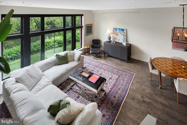 living area featuring baseboards, a notable chandelier, and wood finished floors