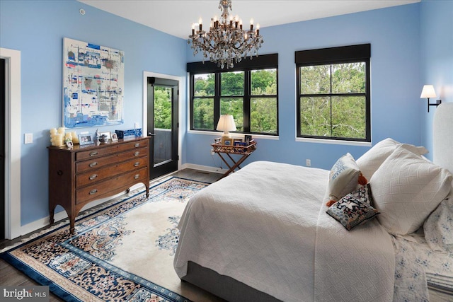 bedroom featuring a chandelier, baseboards, and wood finished floors