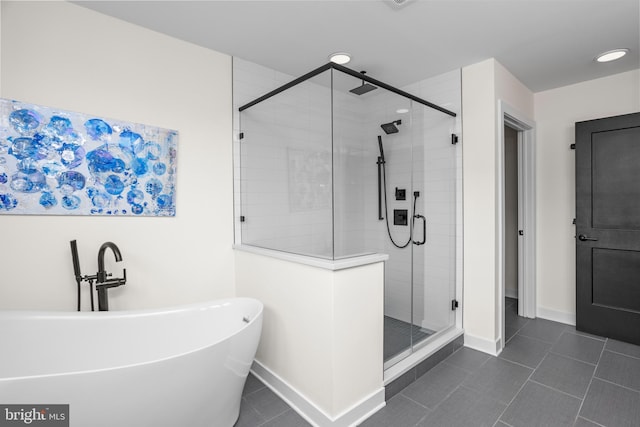 bathroom with tile patterned flooring, a shower stall, a freestanding bath, and baseboards