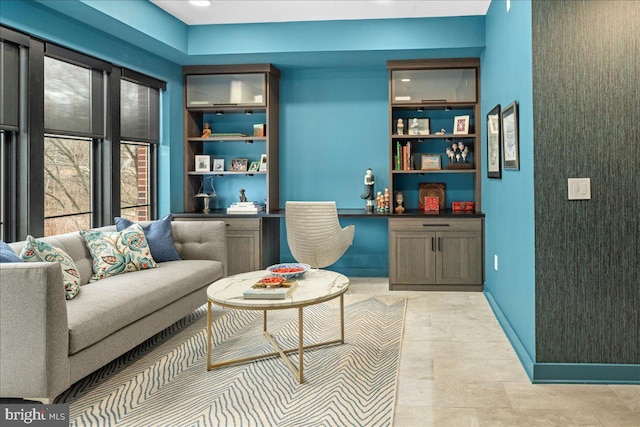 living room featuring baseboards, built in shelves, and built in desk