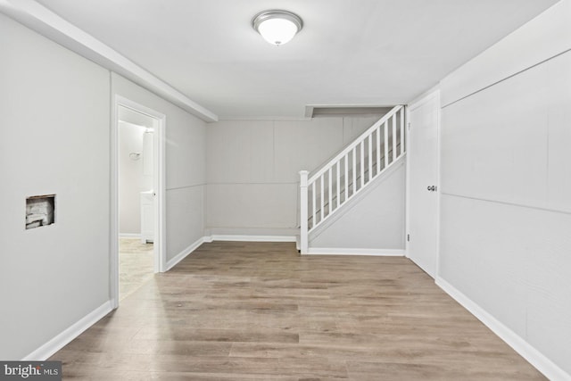 unfurnished room featuring stairs, baseboards, and wood finished floors