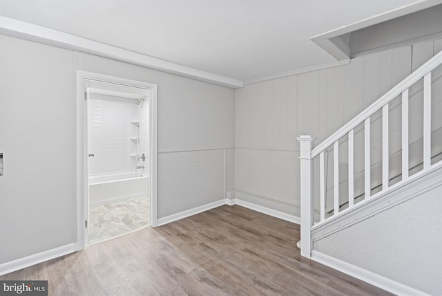 spare room with stairs, baseboards, and wood finished floors