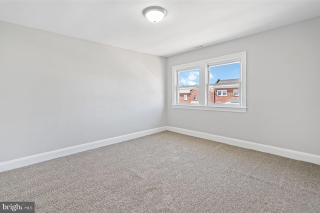 carpeted empty room featuring baseboards