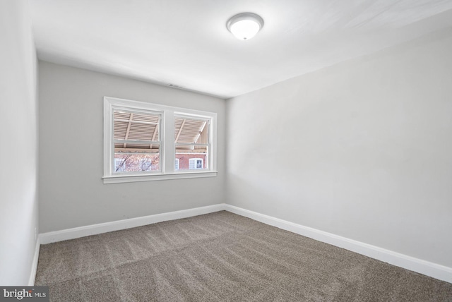 spare room featuring carpet and baseboards