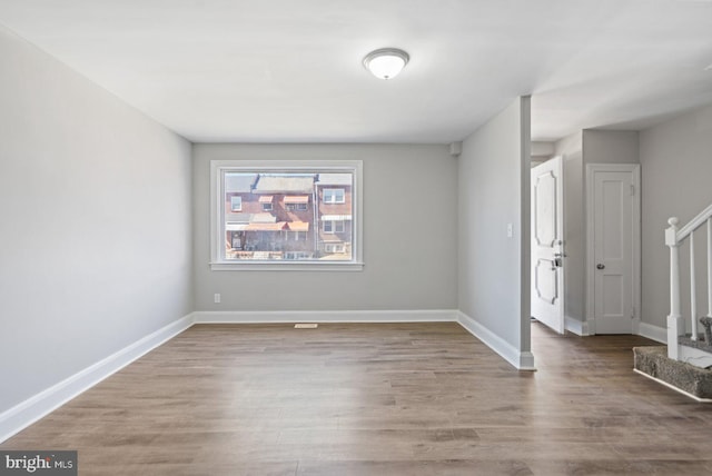 spare room featuring stairs, wood finished floors, and baseboards