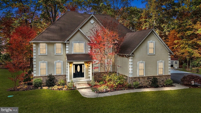 view of front of property with stone siding, stucco siding, a shingled roof, and a front lawn