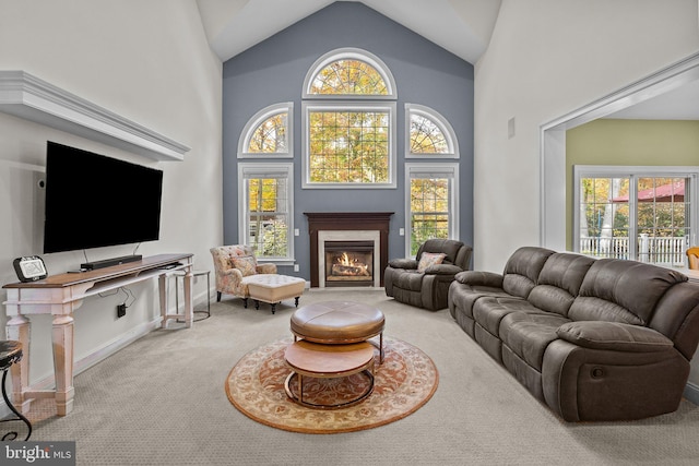 living area with carpet floors, a healthy amount of sunlight, high vaulted ceiling, and a premium fireplace