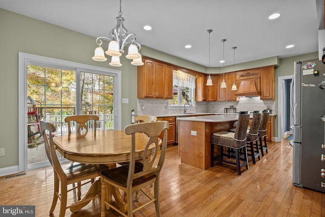 dining space with visible vents, a notable chandelier, recessed lighting, light wood finished floors, and baseboards