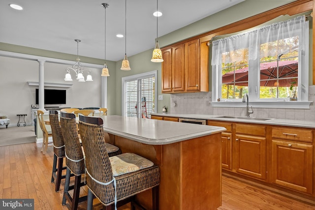 kitchen featuring tasteful backsplash, a center island, light countertops, light wood-style flooring, and a sink