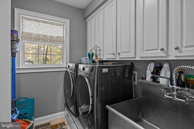 laundry area featuring baseboards, visible vents, washing machine and clothes dryer, cabinet space, and a sink