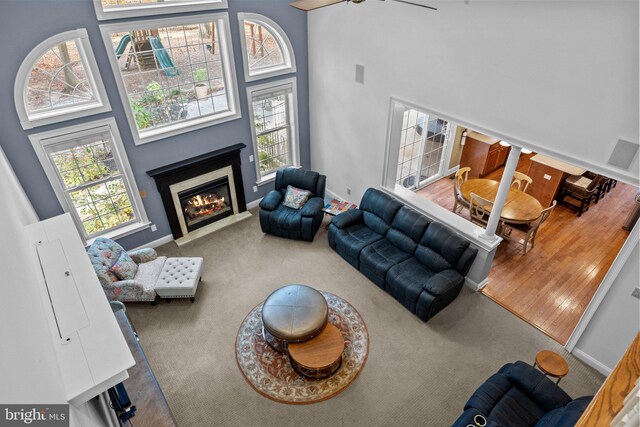 carpeted living room with a wealth of natural light, a fireplace with flush hearth, visible vents, and a towering ceiling