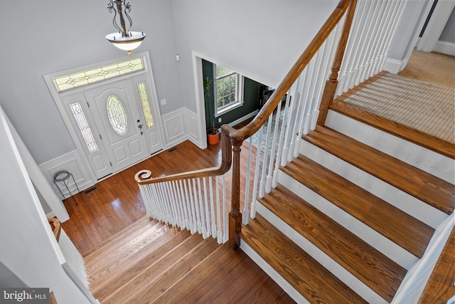 entrance foyer with visible vents, wainscoting, and hardwood / wood-style floors