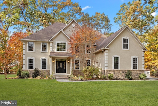 view of front of home featuring stucco siding, stone siding, a front lawn, and a shingled roof