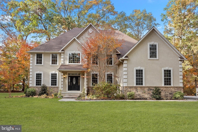 view of front of house with stucco siding, stone siding, a front yard, and a shingled roof