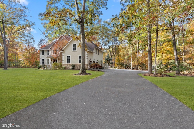 view of property exterior with a yard, stone siding, driveway, and stucco siding