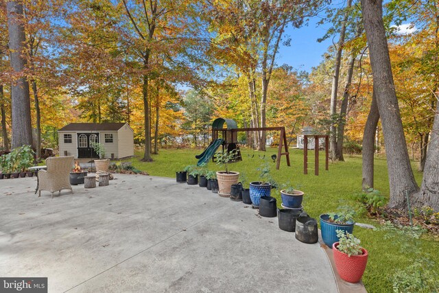 view of patio / terrace with an outdoor fire pit, an outdoor structure, and a playground