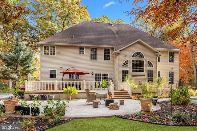 rear view of house featuring a patio area, a wooden deck, and a shingled roof