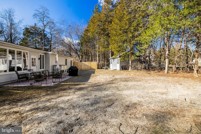 view of yard with fence, an outdoor structure, a storage shed, and a patio area