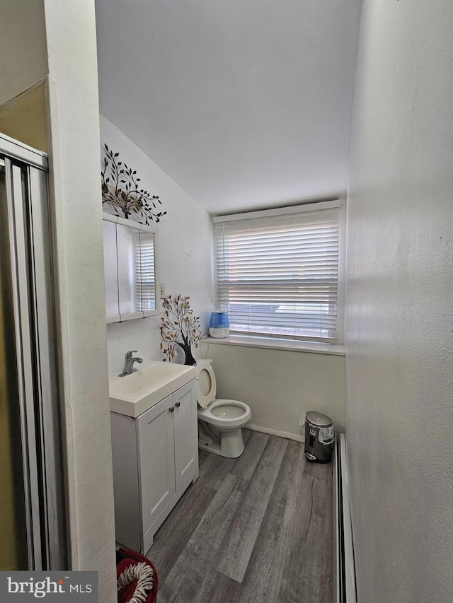 bathroom featuring vanity, wood finished floors, baseboards, a baseboard heating unit, and toilet